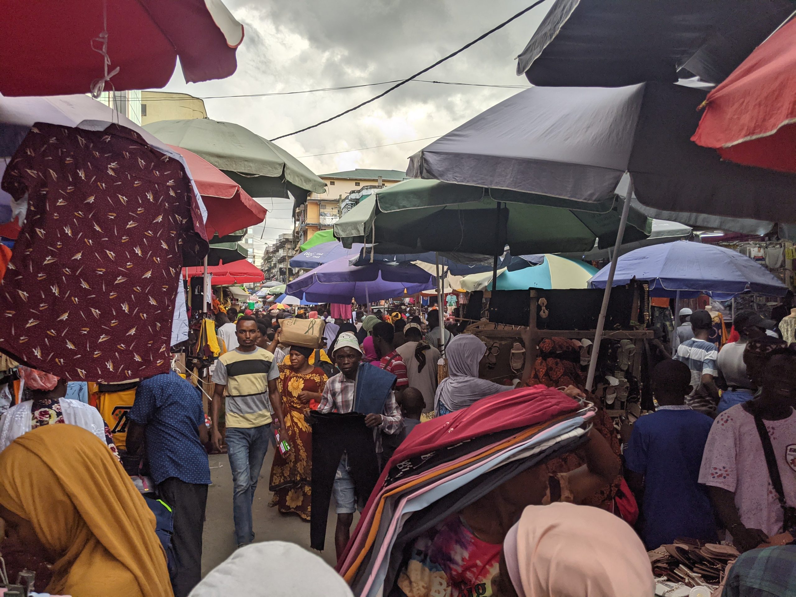 A crowded outdoor market in central Dar es Salaam, where multiple merchants sell goods.