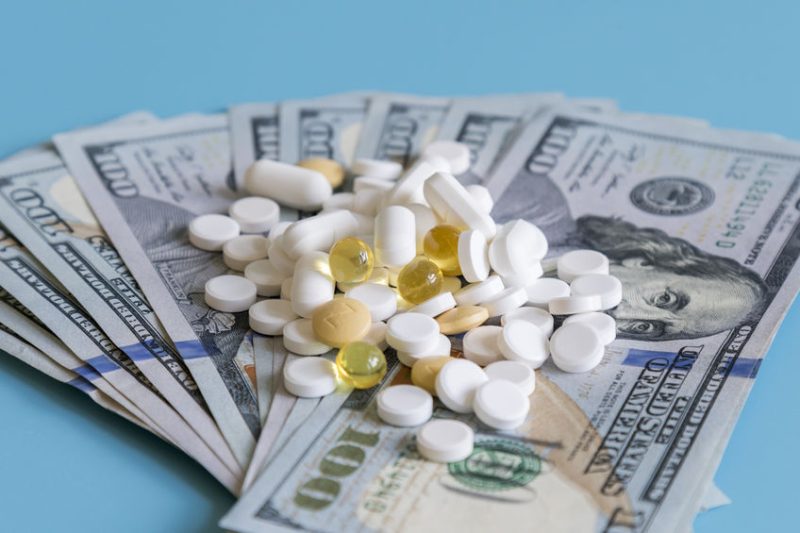 dollars pills medicine. Prescription medicine on dollars for pharmaceutical industry concept of high cost for healthcare and medication, top down view.
