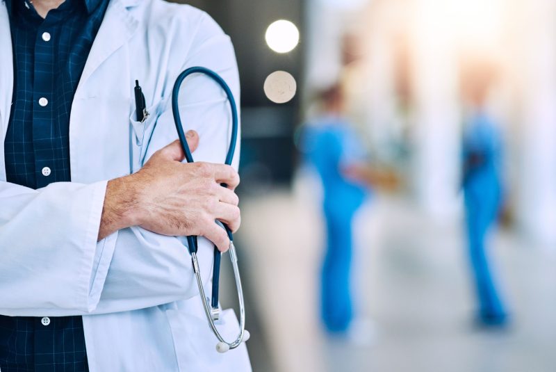 Medical, crossed arms and closeup of a doctor with a stethoscope in a hospital with mockup space. Career, professional and zoom of a male healthcare worker hand with equipment in a medicare clinic.