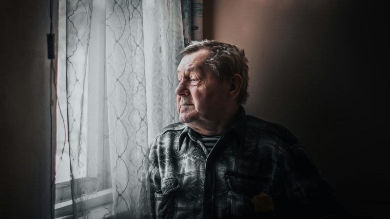 Elderly Man By a Window Looking Outside