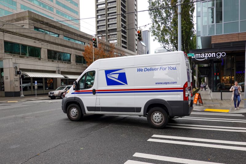 A United States Postal Service Truck making deliveries in an urb