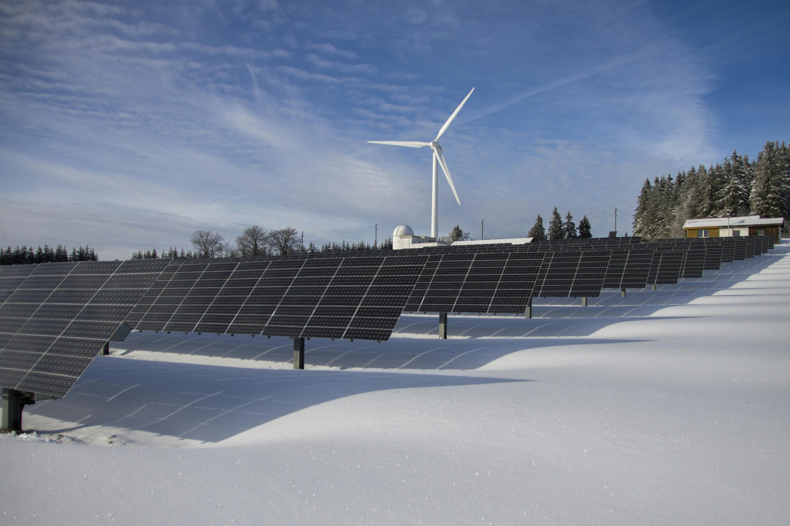 Solar Panels on Snow With Windmill Under Clear Day Sky Solar Panels on Snow With Windmill Under Clear Day Sky