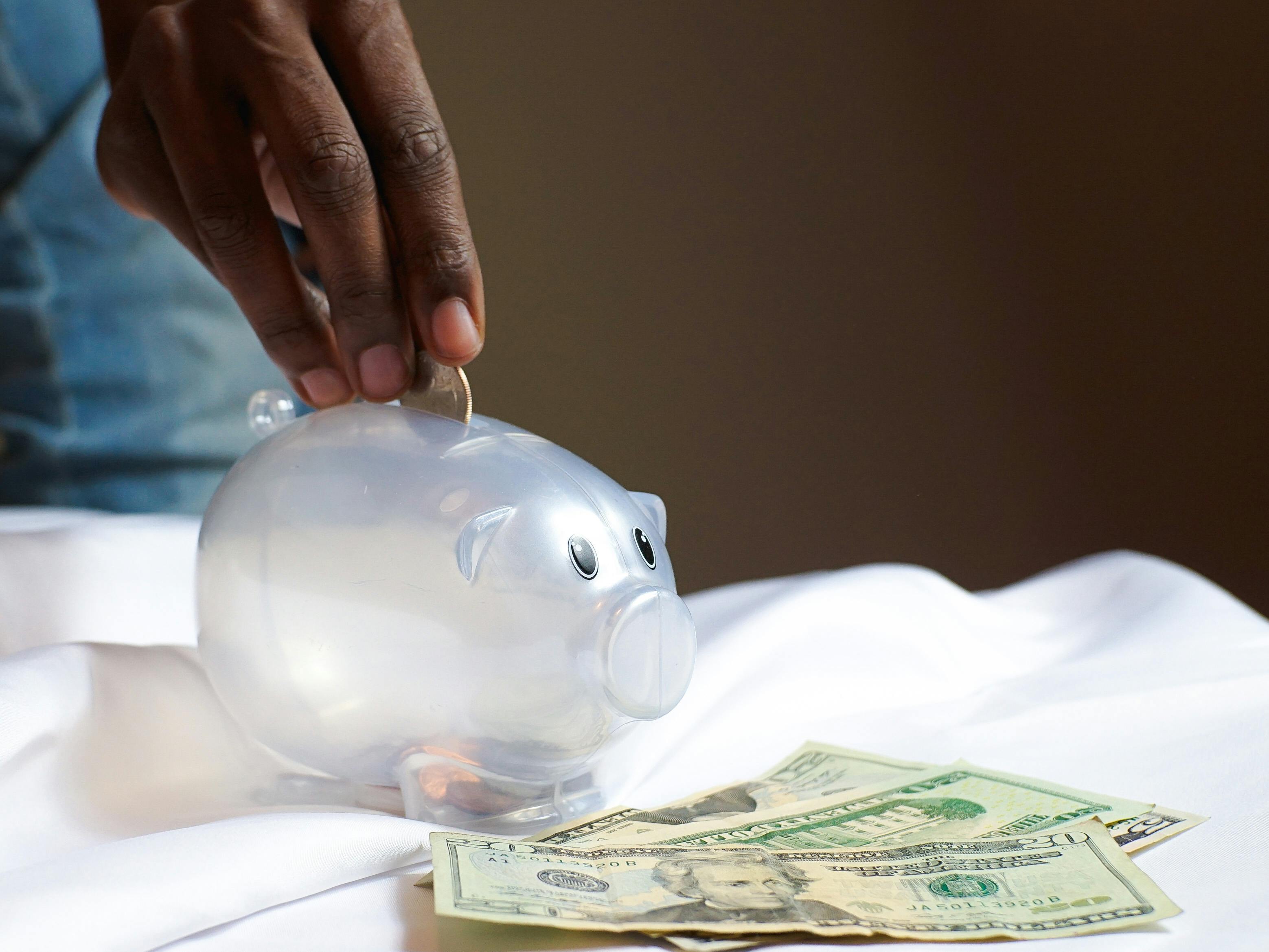 Person Putting Coin in a Piggy Bank Person Putting Coin in a Piggy Bank