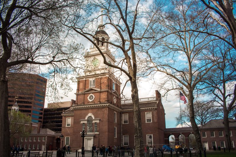 Independence Hall in Philadelphia with a vibrant blue sky and surrounding trees in spring.