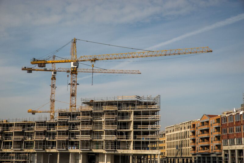City construction site with cranes and partially built structures under a clear sky.