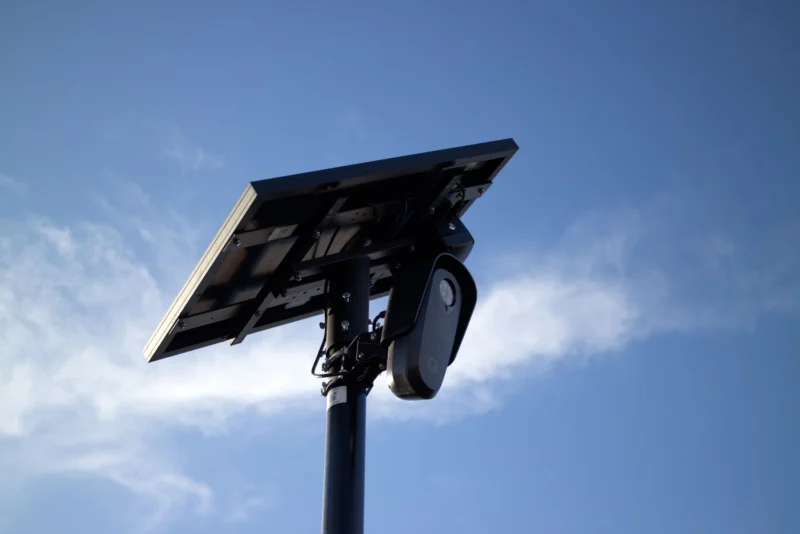 Flock Solar-powered CCTV camera mounted on pole with bright sky background, symbolizing security and technology.